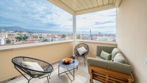 A balcony with a view of a cityscape, a sofa, two chairs, and a table with fruit and drinks. - New Luxury Penthouse 2 steps from downtown (Firenze)