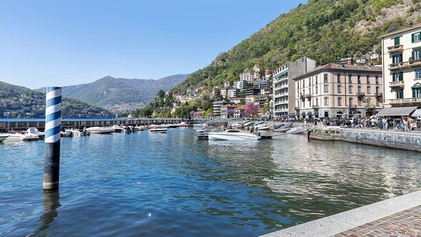 Una orilla con barcos, un muelle y edificios a lo largo de la costa.