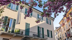 Un edificio con varios balcones, contraventanas y puerta verdes.