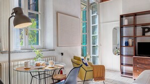 Una habitación con una mesa de comedor, sillas, un sofá, un televisor y una estantería.