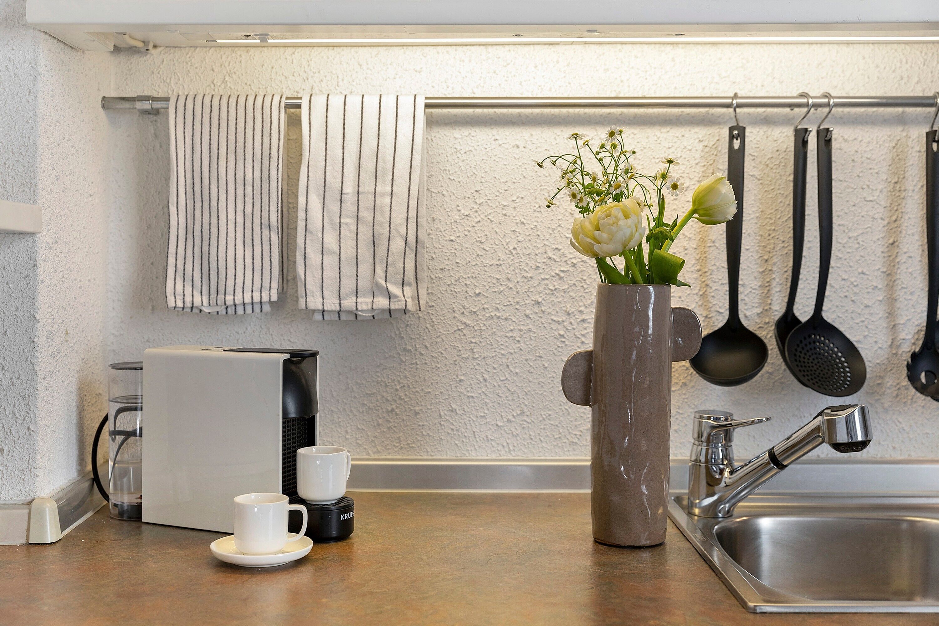 A kitchen with a coffee maker, a sink, and a vase with flowers.