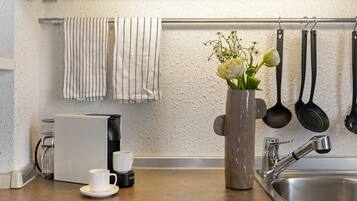 A kitchen with a coffee maker, a sink, and a vase with flowers.