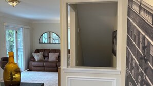 Ein modernes Wohnzimmer mit einer braunen Ledersofa, einem Glastisch und einem großen Fenster.