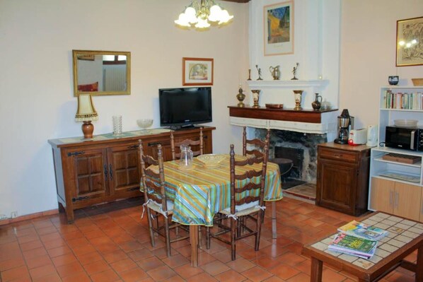 Un comedor con una mesa y sillas de madera, un televisor, una chimenea y una estantería.