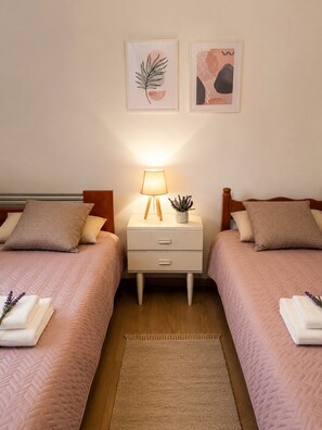 A bedroom with two beds, a bedside table with a lamp, and two wall-mounted pictures. - Cozy, bright home near to the nature for calm moments. (Nea Palatia)