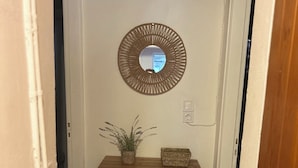 Um corredor com um armário de madeira, um espelho e um vaso de plantas.
