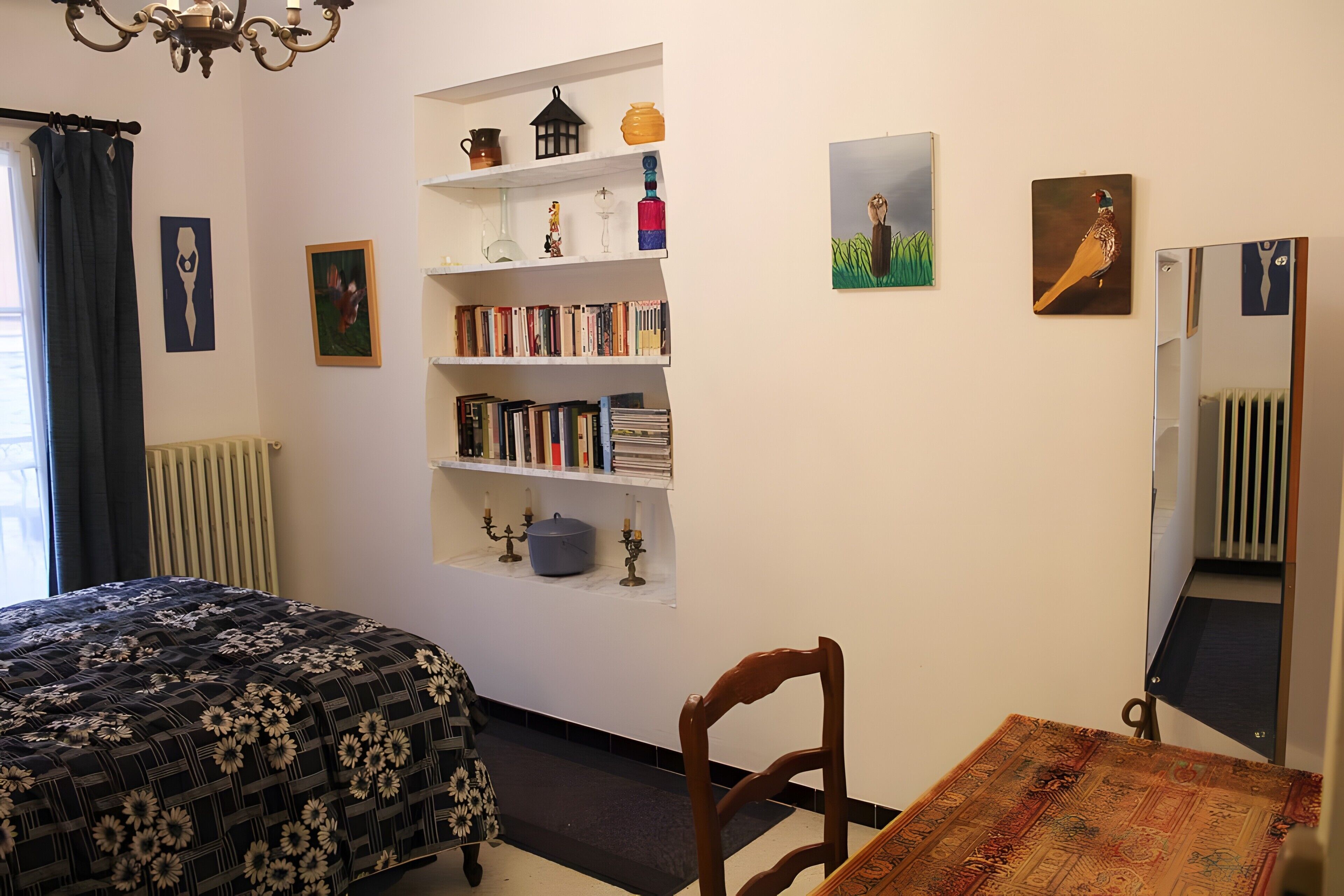 Un dormitorio con una cama, una estantería, una mesa y una silla.
