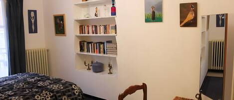 Un dormitorio con una cama, una estantería, una mesa y una silla.