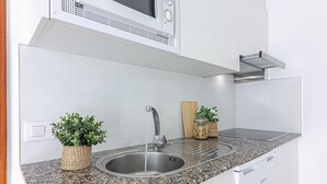 Een keuken met een granieten aanrechtblad, een roestvrijstalen spoelbak en een inbouwmagnetron.