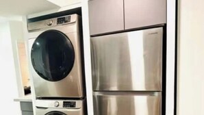 A kitchen with stainless steel appliances, including a washing machine and a refrigerator. - Palm & Paradise Luxe Retreat (Comfort meets City) (Fort Lauderdale)