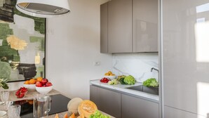 A modern kitchen with grey cabinets, a marble countertop, and a hanging light fixture. - Verdi 1928 A Cozy Wallside Retreat (Lucca)