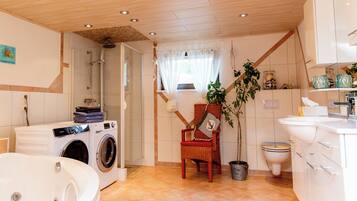 Une salle de bain moderne avec un plafond en bois, une grande baignoire, un lave-linge, des toilettes et un lavabo.