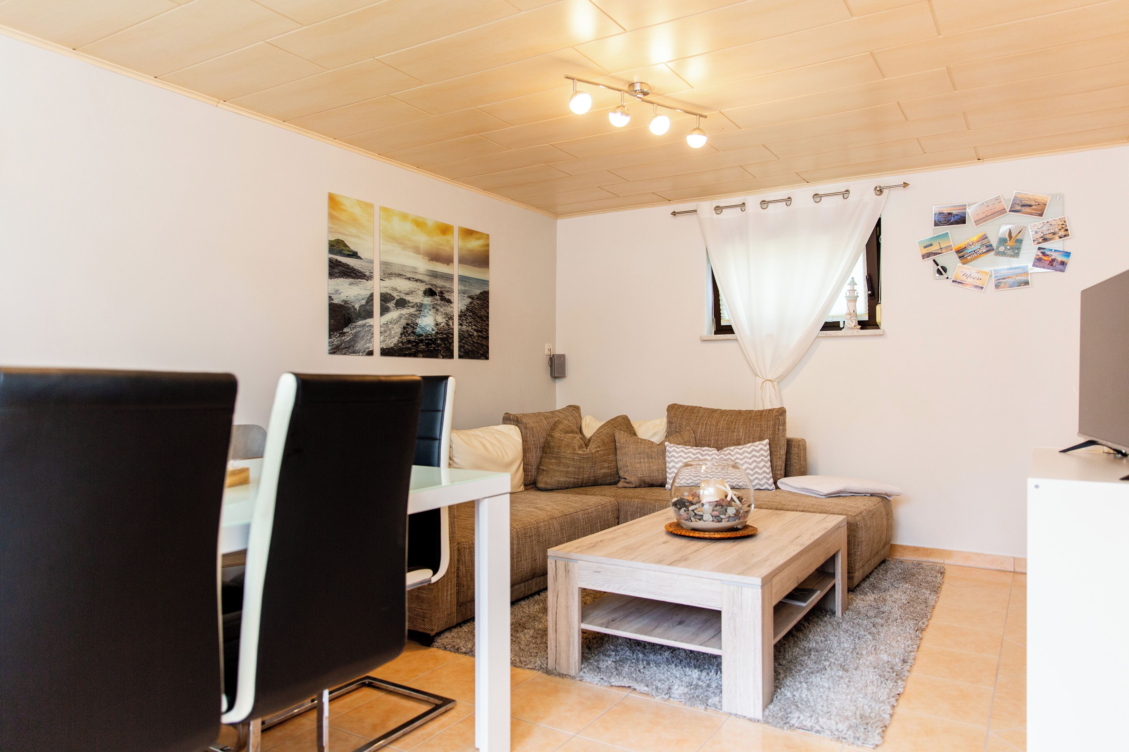 A modern living room with a sofa, coffee table, and a dining area with a chair and table.
