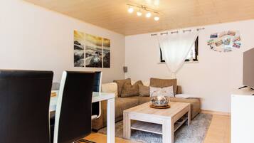 A modern living room with a sofa, coffee table, and a dining area with a chair and table.
