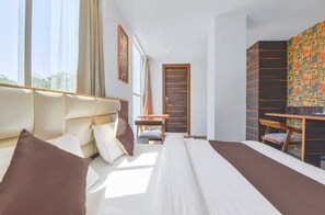 Ein Hotelzimmer mit einem großen Bett, einem Schreibtisch, einem Sessel und einem Bücherregal.