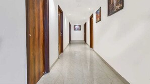 A hallway with wooden doors and a tiled floor, leading to a room with a painting on the wall.