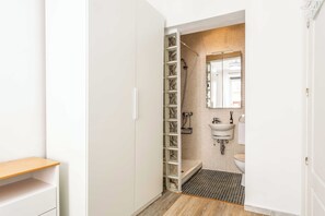 A bathroom with a shower, toilet, sink, and a wooden shelf. - Descubre el encanto de vivir en el corazón de Madrid con este sofisticado apartamento situado en el vibrante barrio de Chueca, justo al lado del emblemático Mercado de San Antón. (Madrid)