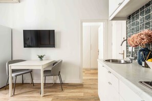 A modern kitchen with a white countertop, a built-in sink, and a flat-screen TV mounted on the wall. - Descubre el encanto de vivir en el corazón de Madrid con este sofisticado apartamento situado en el vibrante barrio de Chueca, justo al lado del emblemático Mercado de San Antón. (Madrid)