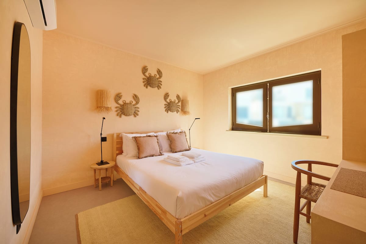 Un dormitorio con una cama grande, mesitas de noche, una silla y una ventana.