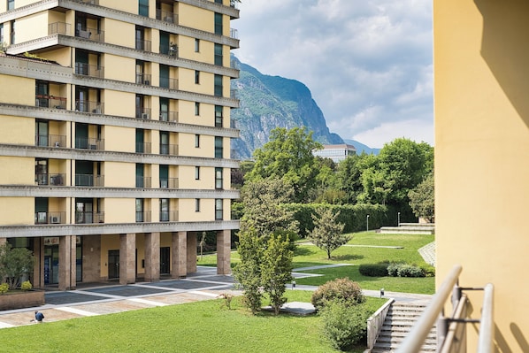 Un hotel a più piani con balconi, un cortile interno e una montagna sullo sfondo.