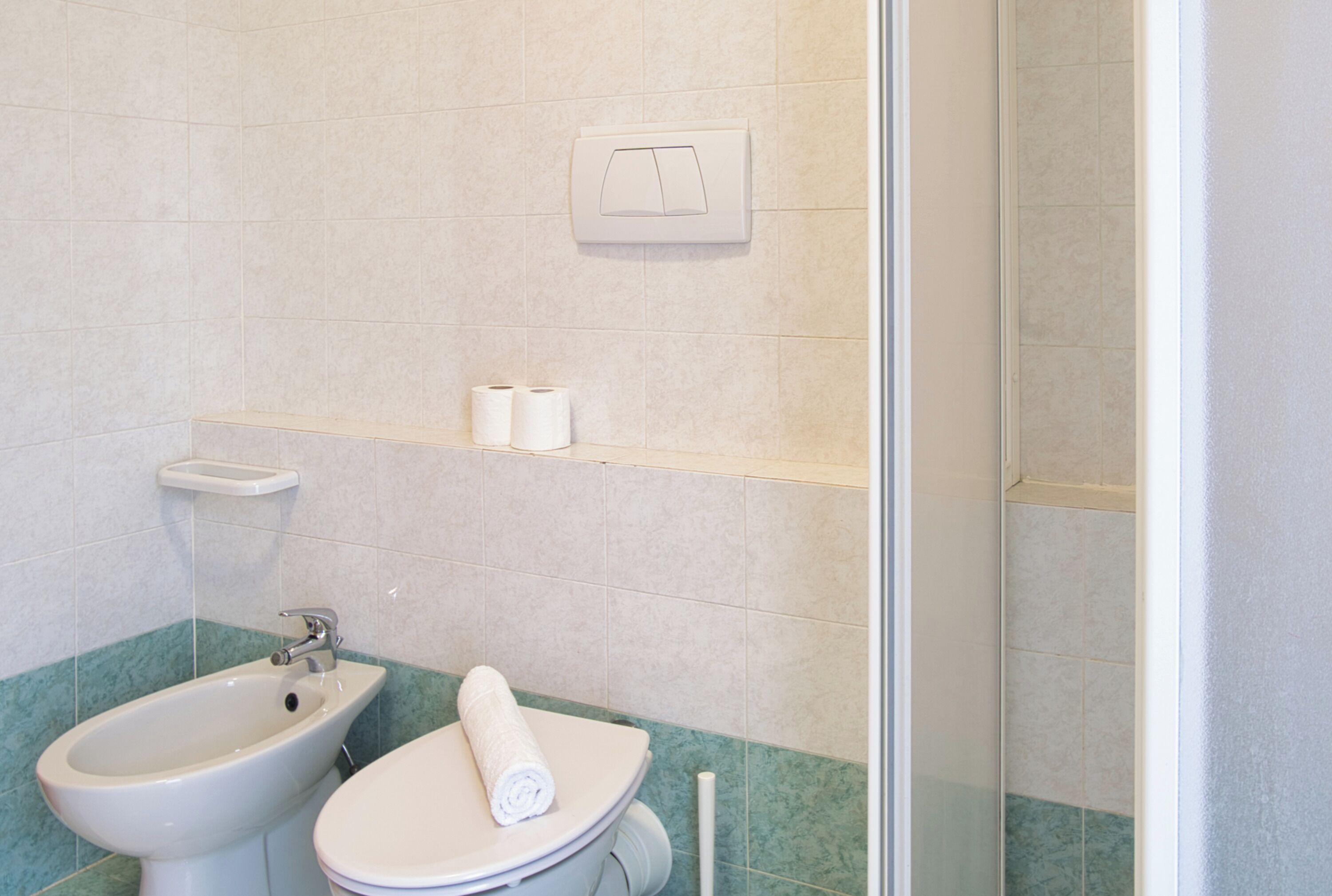 A bathroom with a bidet, toilet, and a towel on the toilet seat.