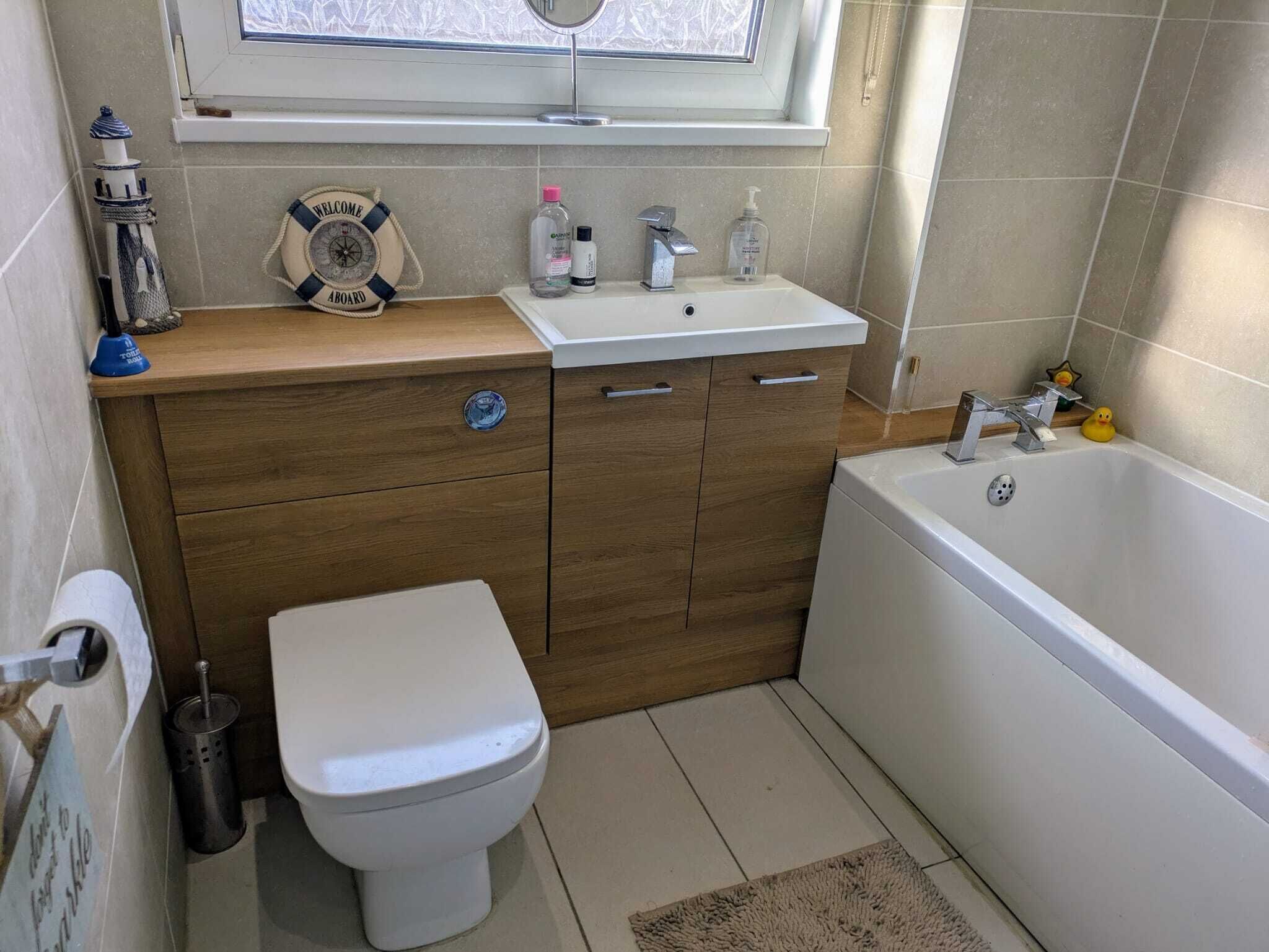 A bathroom with a wooden vanity, a white sink, a toilet, and a bathtub.