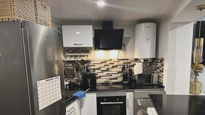 Een moderne keuken met roestvrijstalen apparatuur, een betegelde spatwand en een agenda op de koelkast.