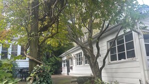 A white house with a stone wall and a tree in the foreground. - Peaceful 2-bedroom house in charming Trussville (Trussville)