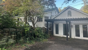 A white building with a stone wall and a pergola. - Peaceful 2-bedroom house in charming Trussville (Trussville)