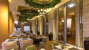 A restaurant with indoor seating, large windows, and hanging greenery. - Ace of Hua Hin Resort - Ace Junior Suite Pool Access (Cha-am)
