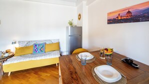 A compact living space with a sofa, dining table, and a refrigerator.