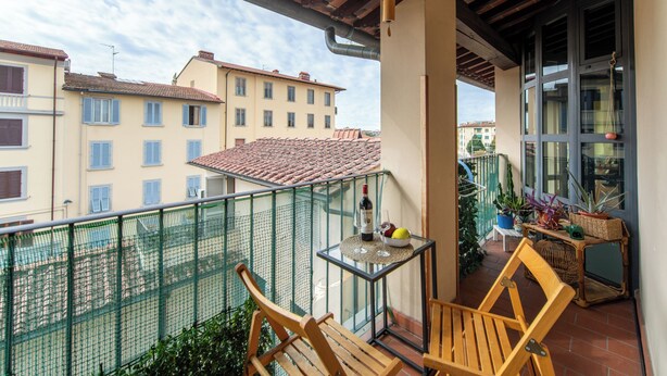 A balcony with a table, chairs, and potted plants.