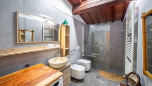 A modern bathroom with a wooden vanity, a large mirror, a freestanding bathtub, a toilet, and a shower enclosure.