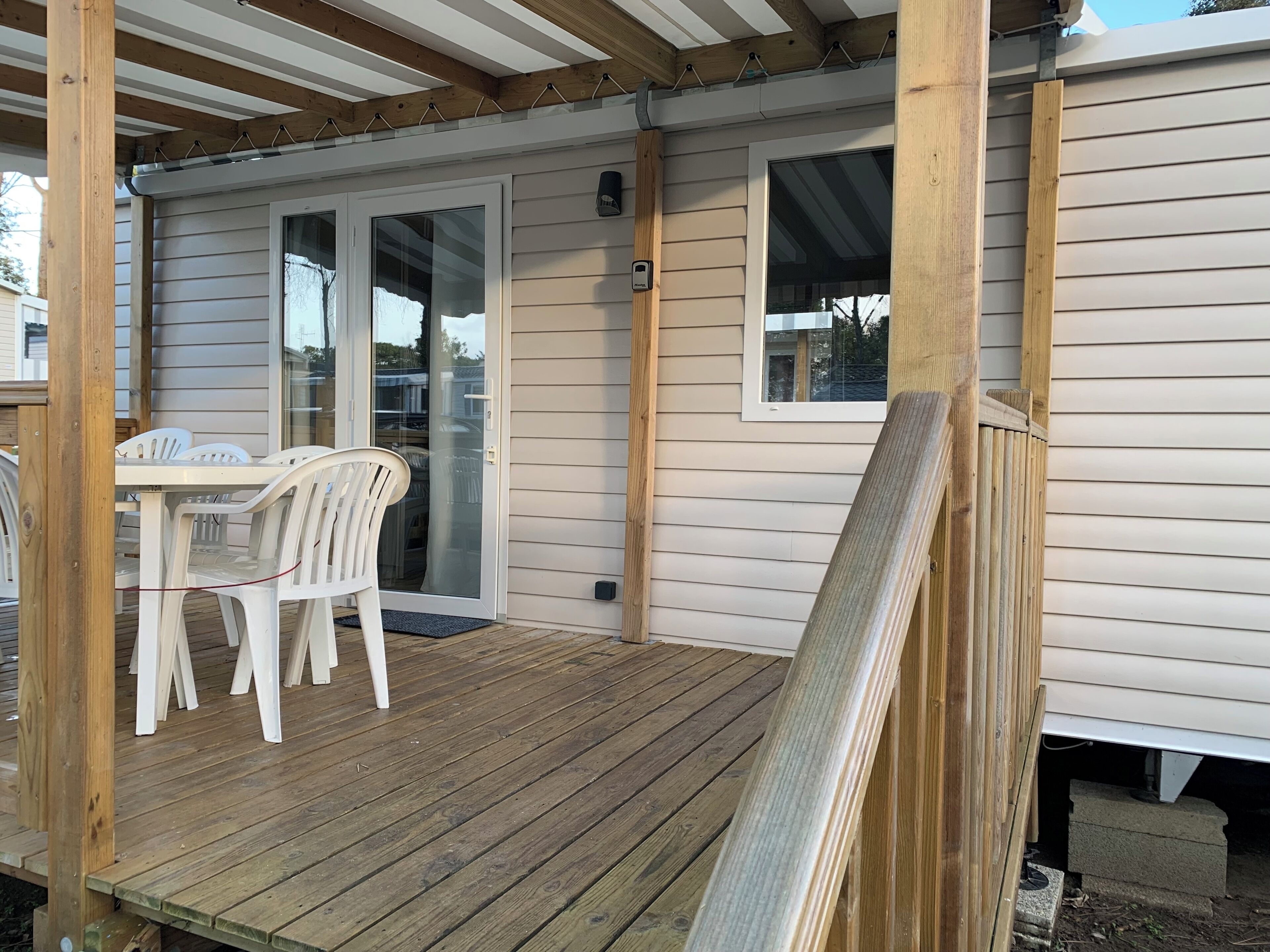A covered patio with a table and chairs, wooden deck, and a sliding glass door leading to a covered area.