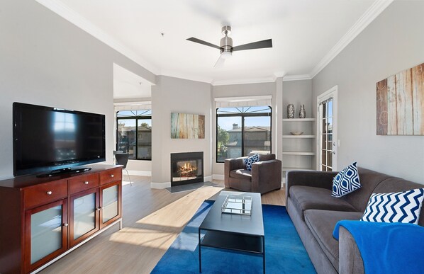A modern living room with a flat-screen TV, a fireplace, a ceiling fan, a sofa, and a coffee table. - Pure Suites Scottsdale Kierland Commons Scottsdale Quarter 2 Bed Pool Gym (Scottsdale)