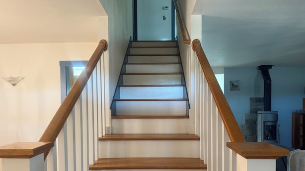 A wooden staircase with white railings and a blue wall in the background. - Charming 3-bedroom country home (Manor)