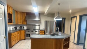 A modern kitchen with wooden cabinets, stainless steel appliances, and a central island. - Charming 3-bedroom country home (Manor)