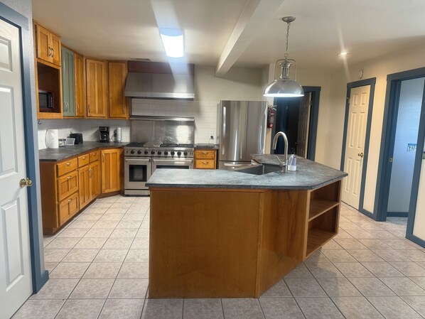 A modern kitchen with wooden cabinets, stainless steel appliances, and a central island. - Charming 3-bedroom country home (Manor)