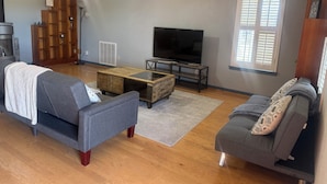 A living room with two sofas, a coffee table, a TV, and a fireplace. - Charming 3-bedroom country home (Manor)