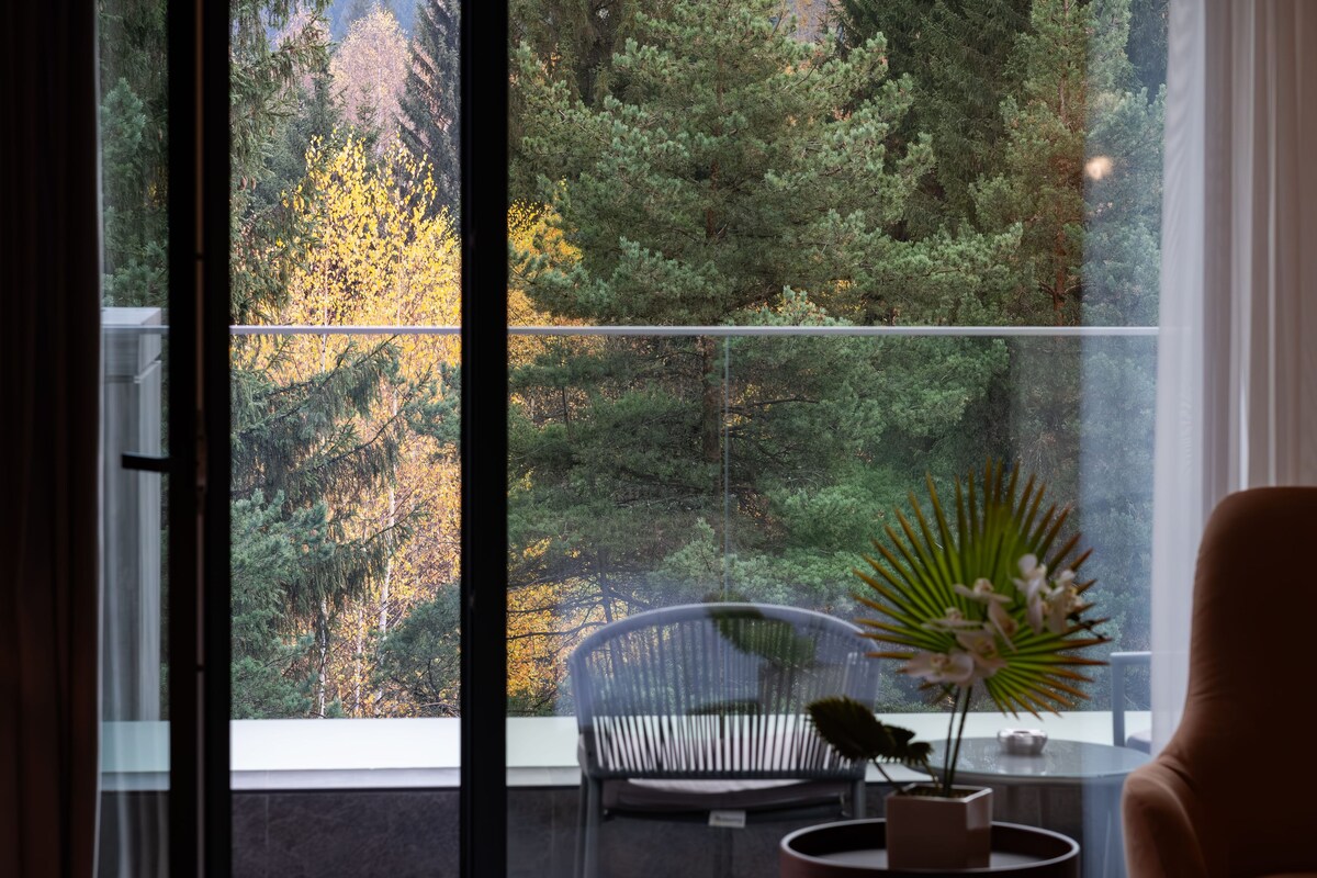 A room with a large window overlooking a forested area.