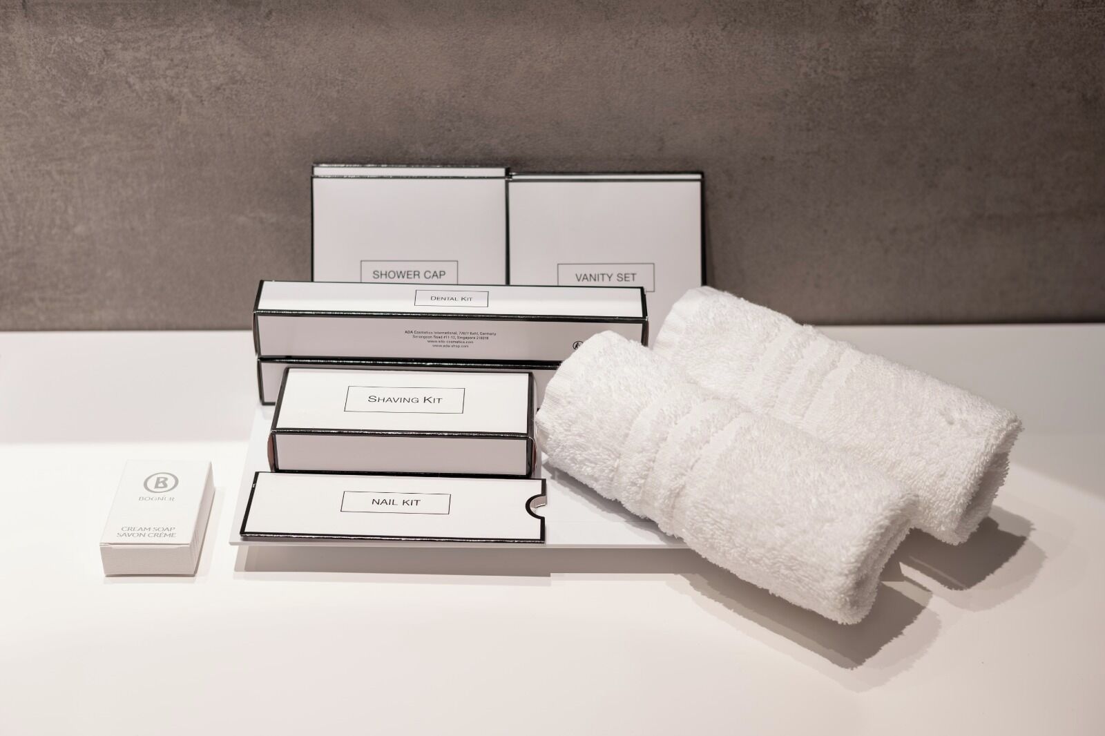 A set of toiletry boxes and a towel on a white surface.