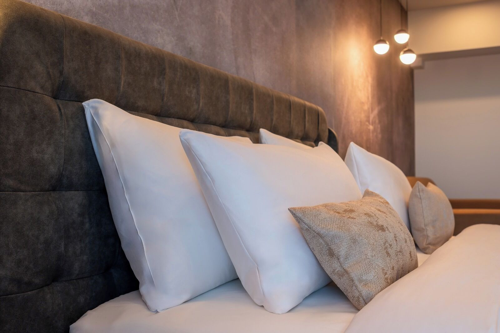 Una cama con cabecera capitonada y varias almohadas.
