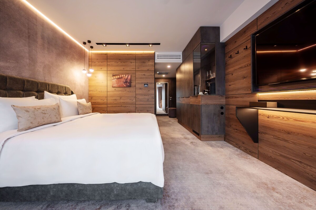 A modern bedroom with a large bed, wooden paneling, and built-in storage.