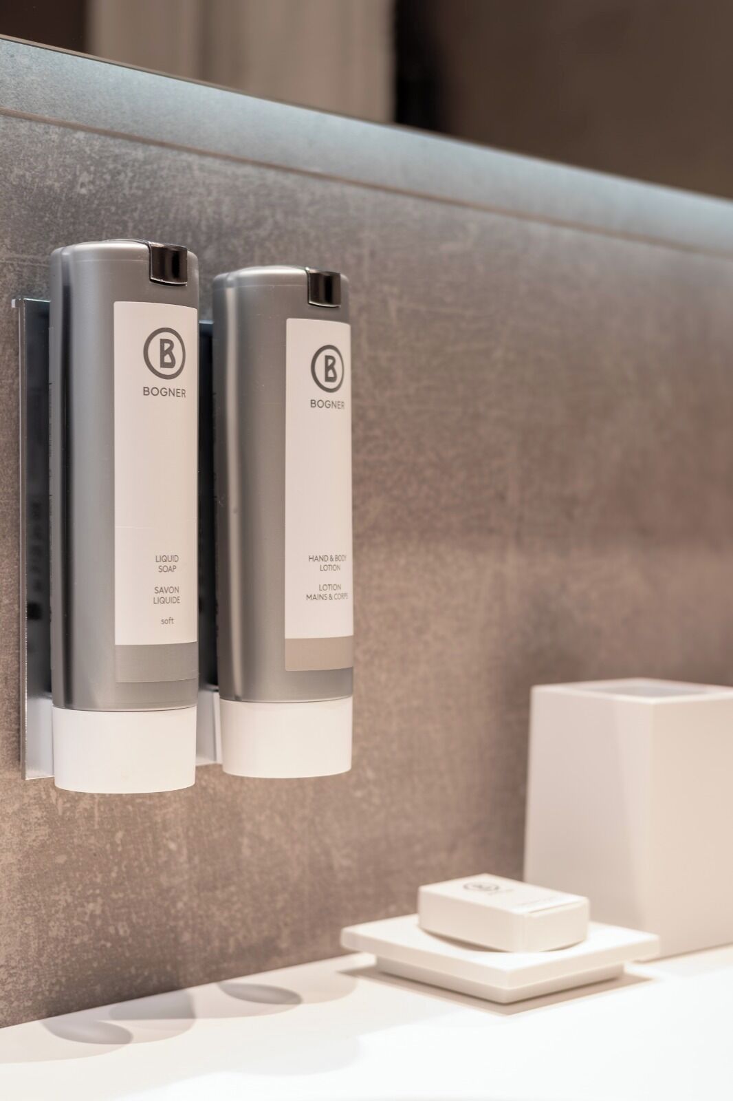 Two bottles of Bogner liquid soap and hand & body lotion mounted on a wall.