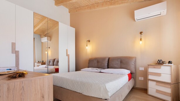 A bedroom with a bed, a dresser, a mirror, and an air conditioner. - Apartment 'Lu Furru - Carasau' with Air Conditioning (Telti)