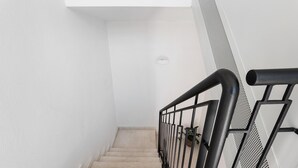 A staircase with a black metal railing, beige carpeted steps, and a white wall. - Apartment 'Lu Furru - Carasau' with Air Conditioning (Telti)