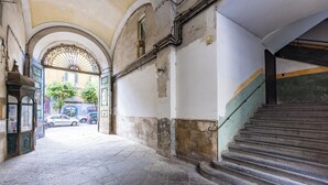 A narrow corridor with a stone floor, a staircase on the right, and an arched doorway at the end.