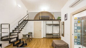 A modern room with a wooden floor, a staircase, a bed, a small table, and a chair.