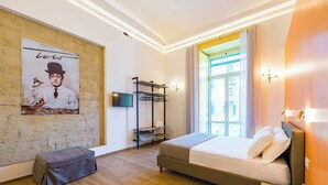 A modern hotel room with a large bed, a small seating area, a TV, and a window with curtains. - Guest Rooms Bellini - Totò - Studios Superior (Naples)