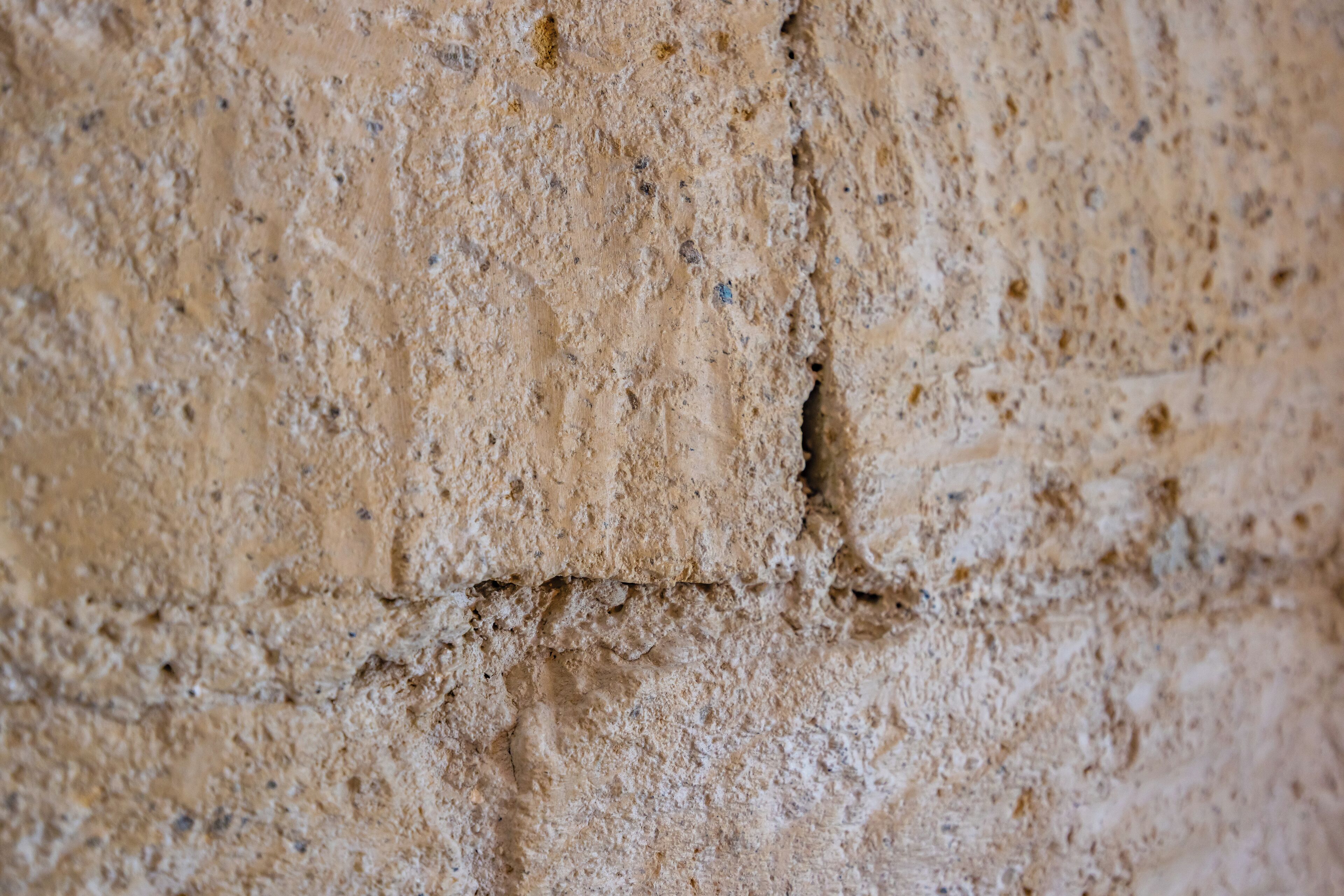Primer pla d'una paret amb superfície rugosa i fissures visibles.
